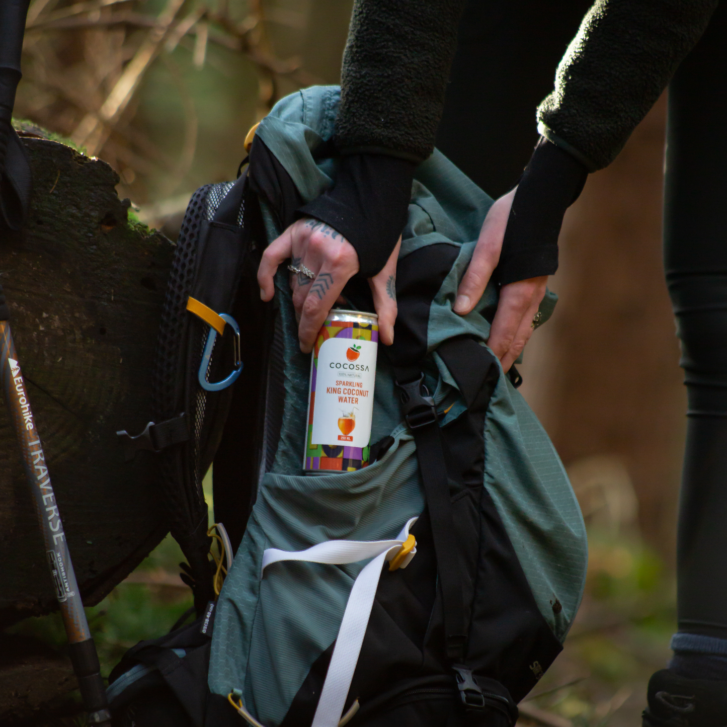 Hiker packing a Cocossa Sparkling 100% Natural King Coconut Water 250ml Can to her back pack.
